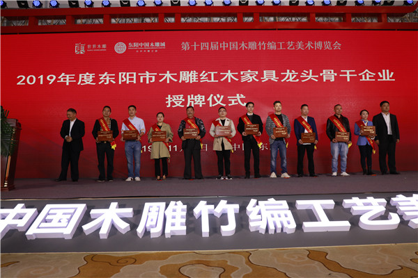 双洋红木董事长王海洋（左三）上台领取“2019年度东阳市木雕红木家具骨干企业”荣誉